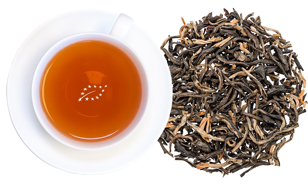 Weiße Tasse mit schwarzem Tee und losen Teeblättern