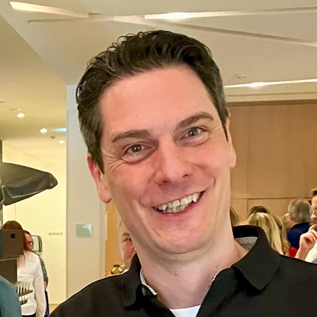 Porträt eines lächelnden Mannes mit dunklem Haar und Polohem
