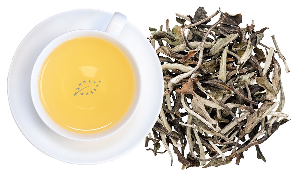 Weiße Teetasse neben losen weißen Teeblättern