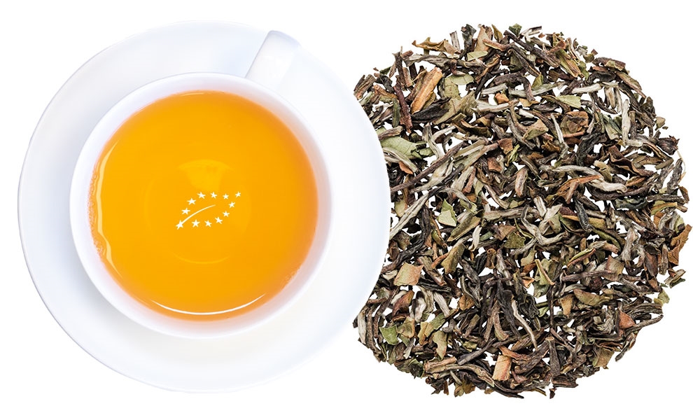 Weiße Tasse Darjeeling-Tee neben losem Blatttee