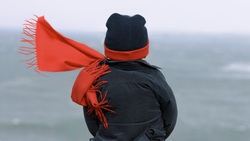 Kräutertee Kältezeit Junge mit Winterjacke und rotem Schal und Mütze von hinten fotografiert
