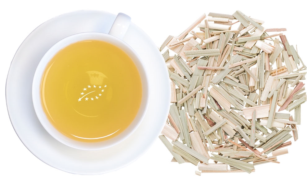 Weiße Tasse Lemongras-Tee neben getrocknetem Zitronengras