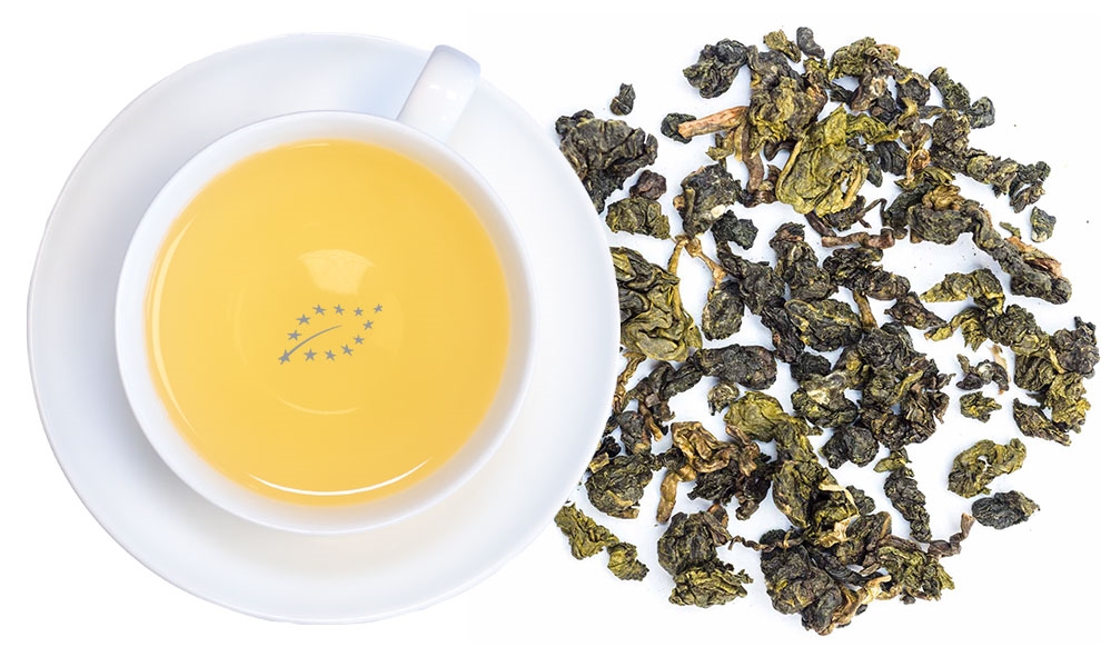 Weiße Tasse Oolong-Tee neben losen Teeblättern