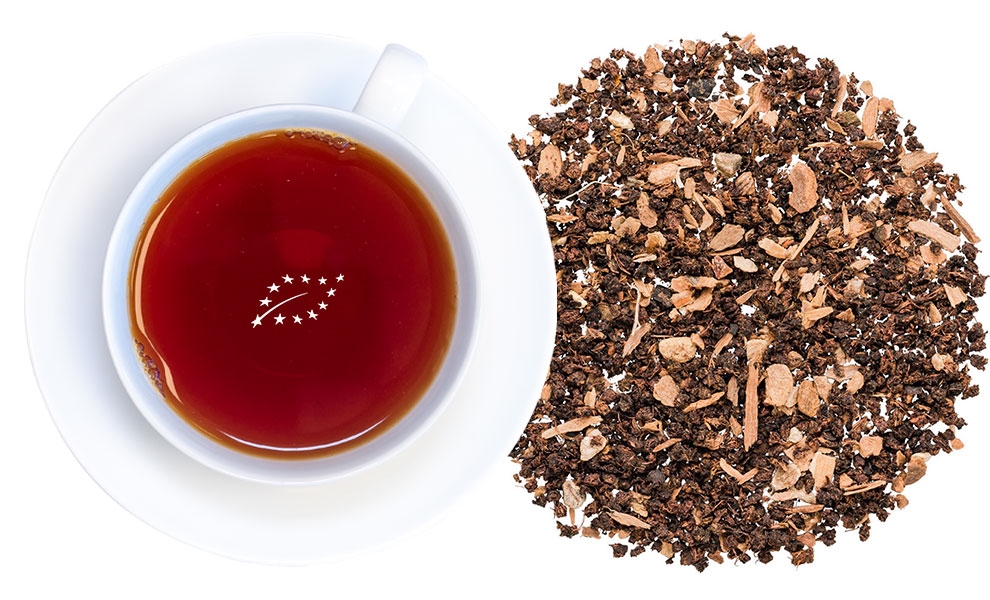 Weiße Tasse mit Kräutertee und losem Tee daneben
