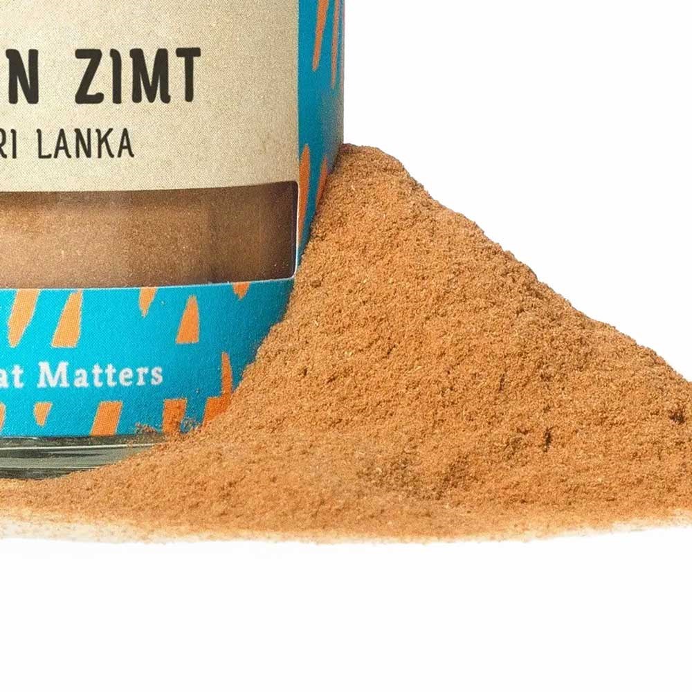 Glas mit gemahlenem Ceylon Zimt aus Sri Lanka, daneben ein Haufen Zimtpulver