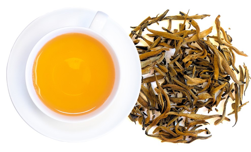 Tasse goldener Schwarztee mit losen Teeblättern