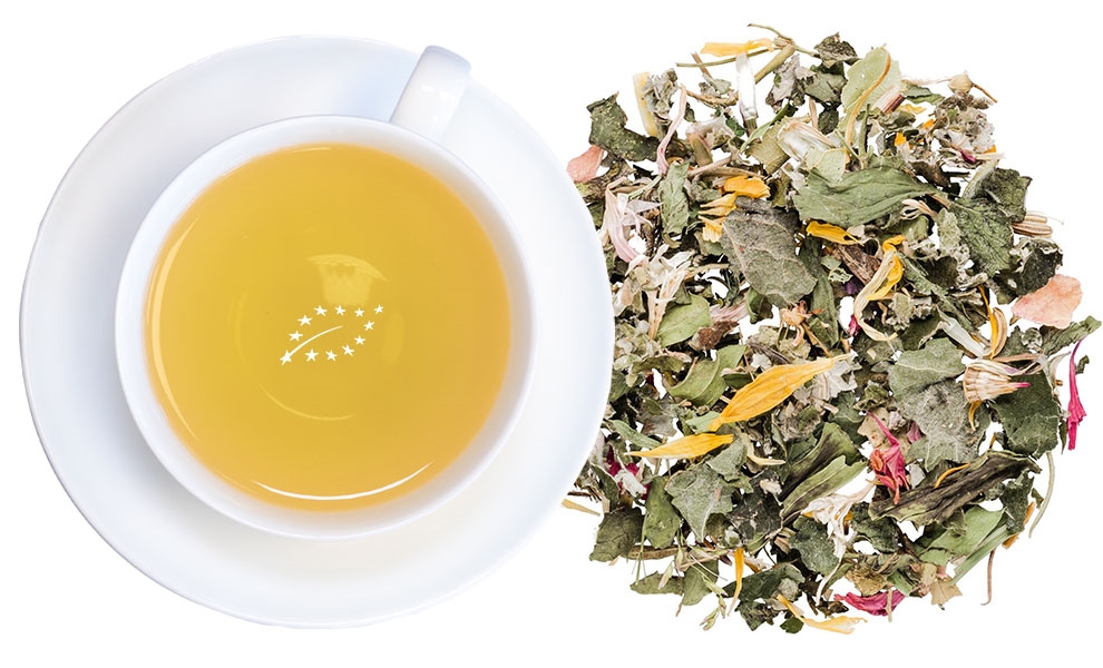 Weiße Tasse Kräutertee neben loser Kräutermischung