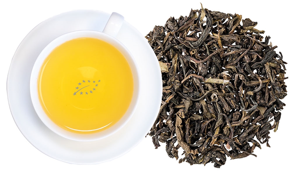 Weiße Tasse grüner Tee neben losen Teeblättern