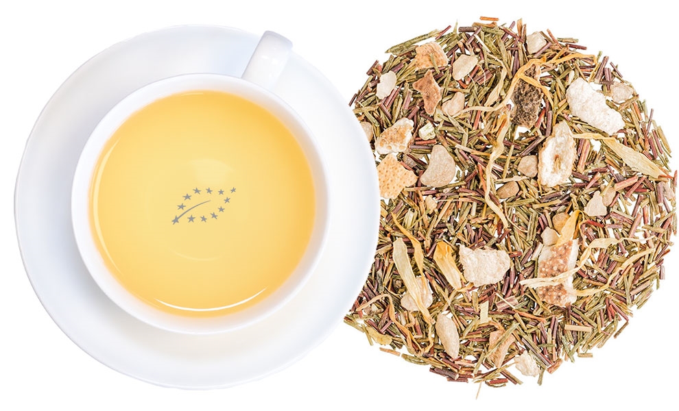 Weiße Tasse Kräutertee neben losem Tee