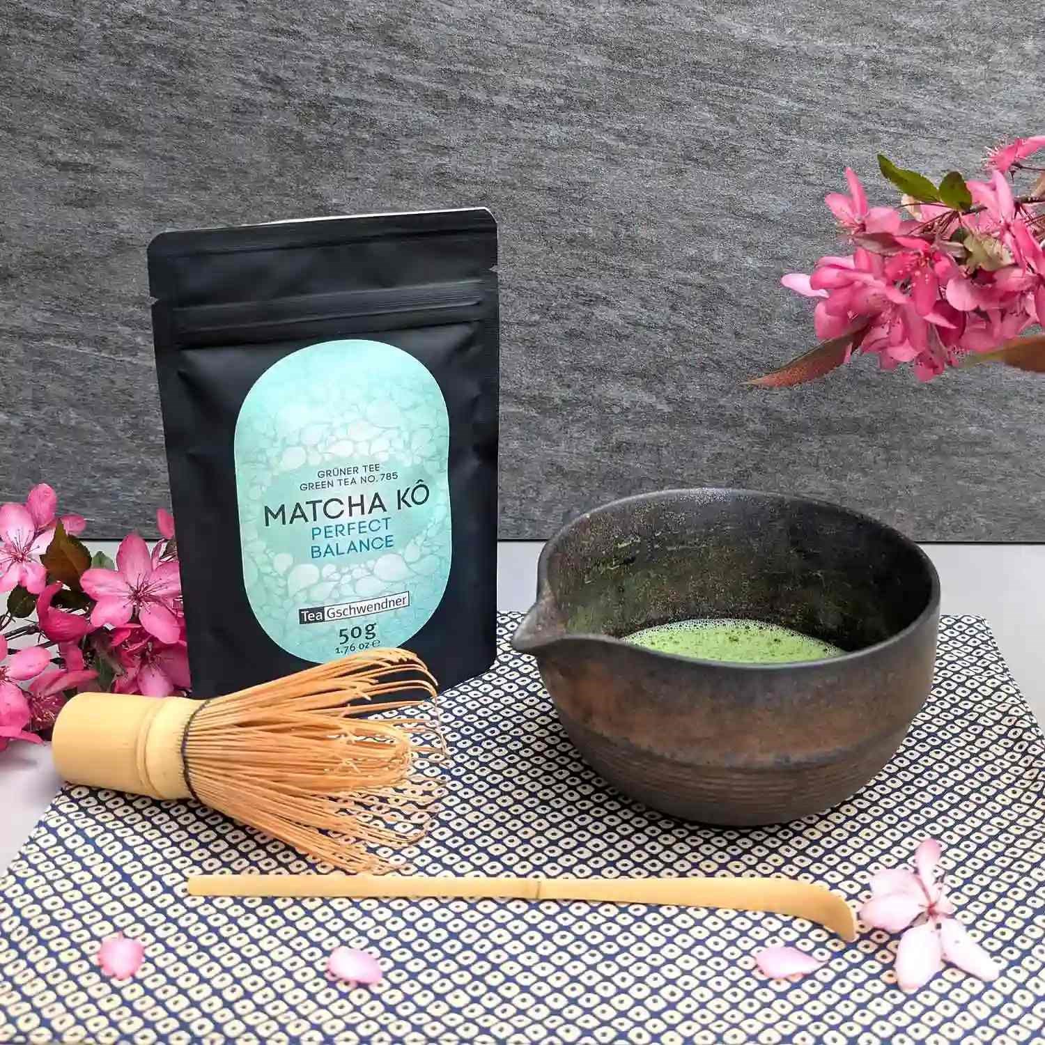 Japan Matcha Kô "Perfect Balance" in schwarzer Packung mit Matcha-Schale, grünem Tee und Bambusbesen – ausgewogener japanischer Matcha für puren Genuss, Latte und Desserts.