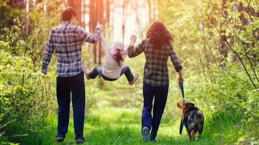 Mann und Frau mit Kind und Hund beim Waldspaziergang