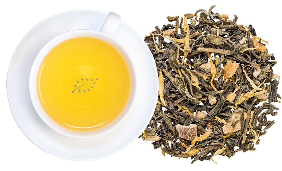 Weiße Tasse grüner Tee neben losen Teeblättern