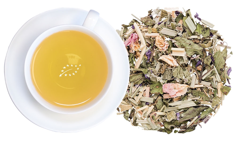 Weiße Tasse Kräutertee neben loser Kräuterteemischung
