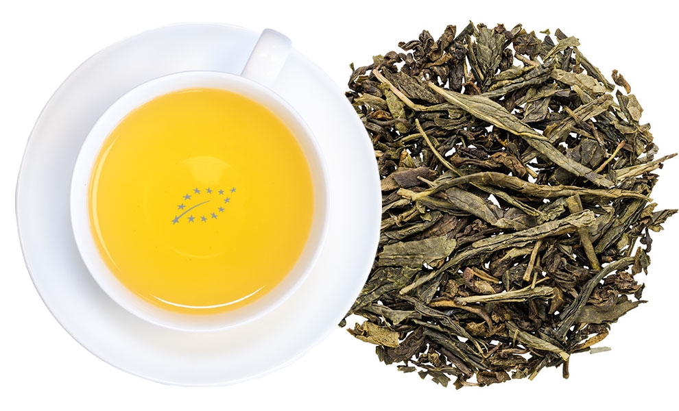 Tasse grüner Tee neben losem Grüntee