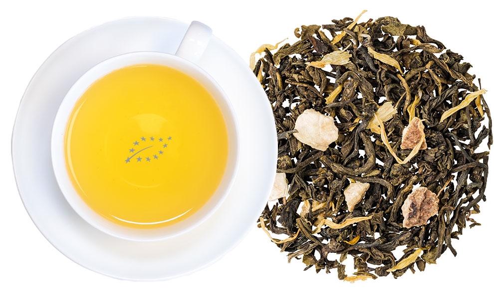 Tasse grüner Tee mit losem Früchtetee daneben