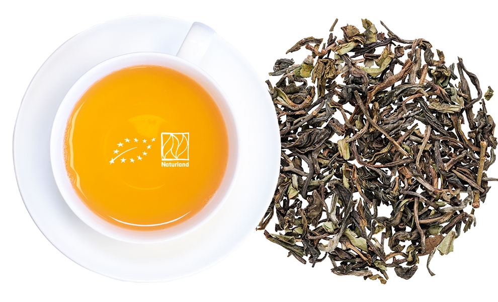 Weiße Tasse Tee neben losem Schwarztee
