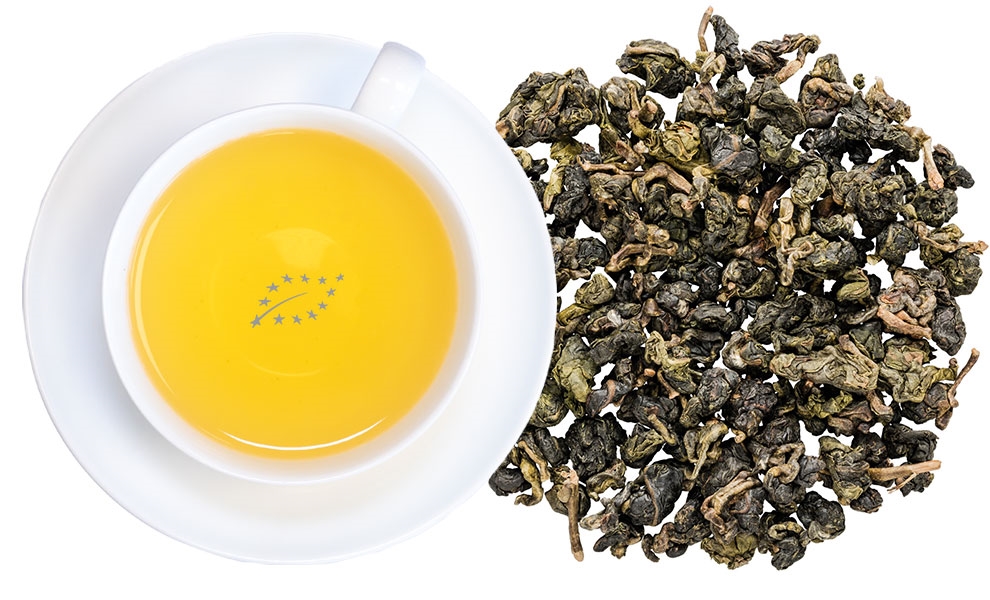 Weiße Tasse Oolong-Tee neben losen Teeblättern
