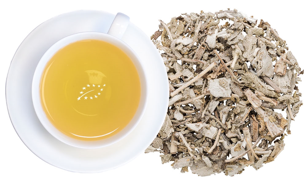 Weiße Tasse Kräutertee neben losen Blättern