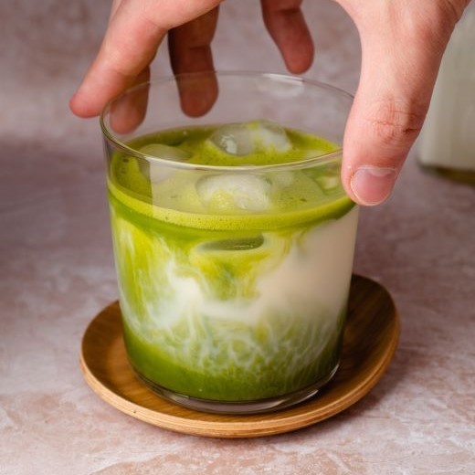 Glas mit Matcha Latte Eiskaffee und Eiswürfeln