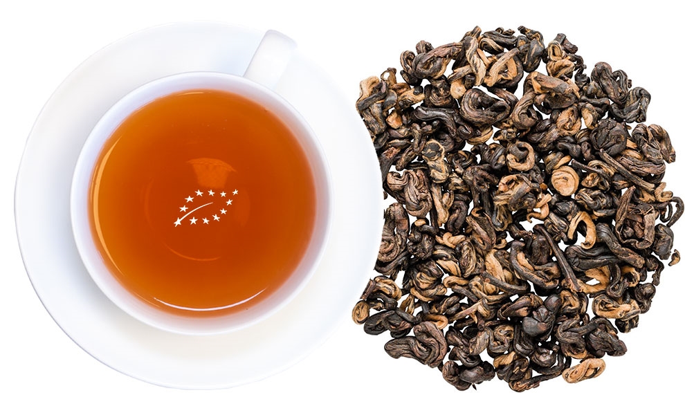 Weiße Tasse mit Schwarzem Tee und losen Teeblättern