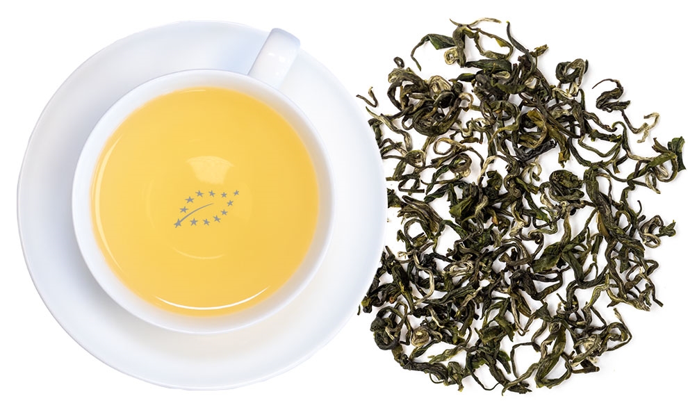 Weiße Tasse grüner Tee neben losen Teeblättern