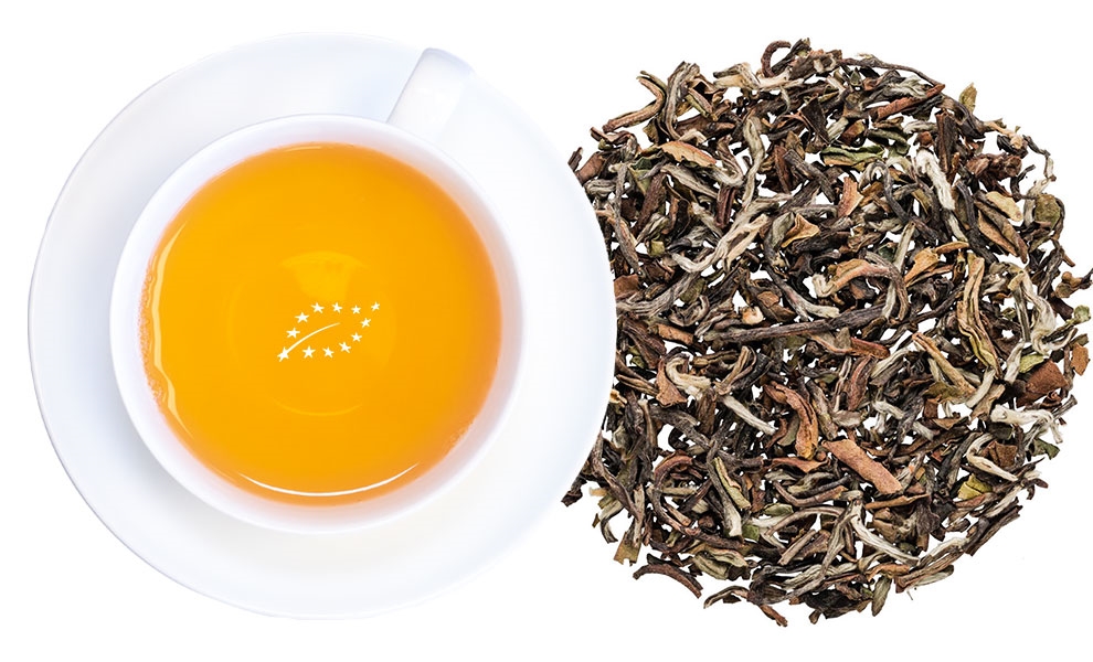 Weiße Tasse Darjeeling-Tee neben losem Blatttee