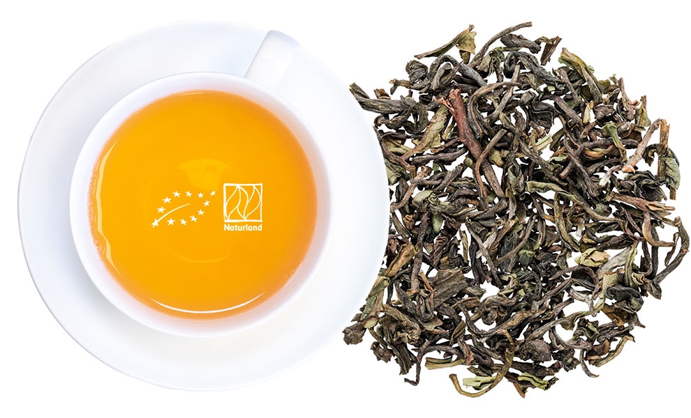 Weiße Teetasse mit losem Blatttee daneben