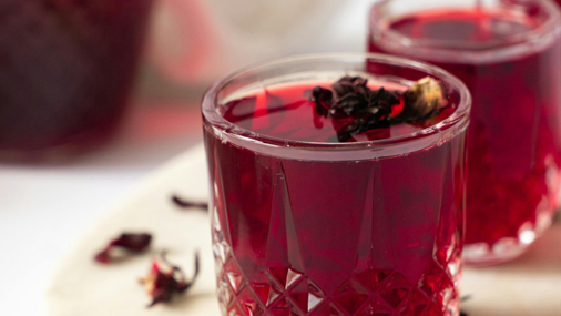 Früchtetee Willi Vanilli dunkelroter Tee in einem Glas mit getrockneten Hibiskusblüten