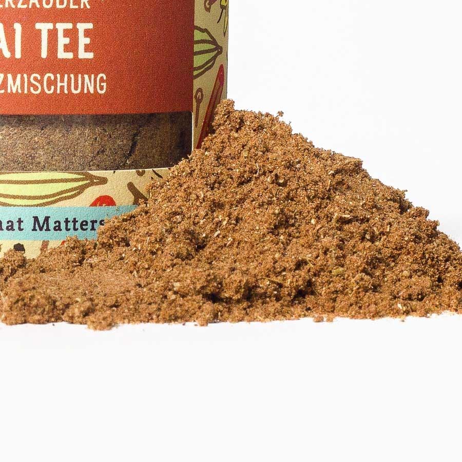 Nahaufnahme einer aromatischen Chai-Tee-Gewürzmischung im Glas mit losem Pulver im Vordergrund
