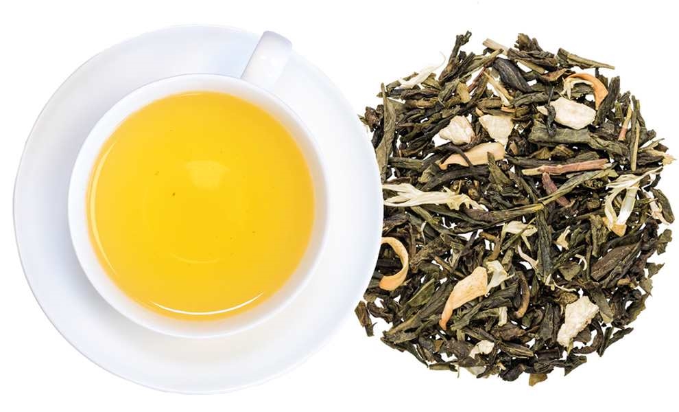 Tasse grüner Tee neben losen Teeblättern