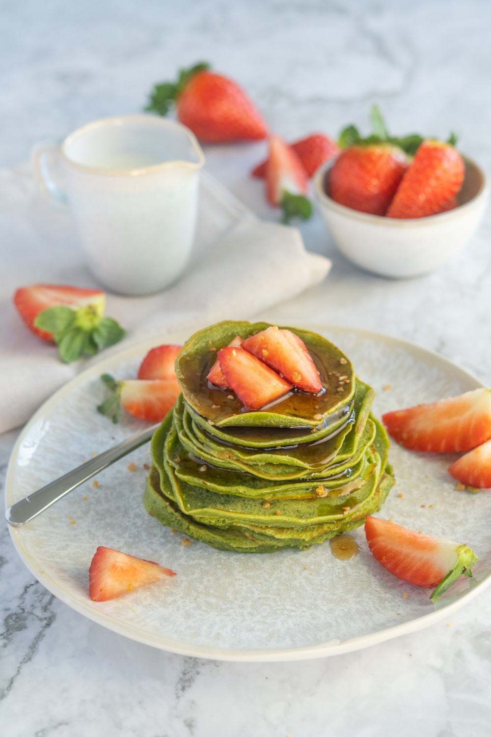 Gestapelte grüne Matcha-Pfannkuchen mit Erdbeerscheiben und