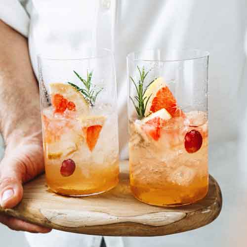 Zwei Gläser mit fruchtigem Cocktail und Eis auf Tablett