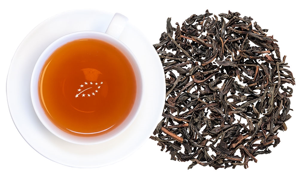 Weiße Tasse mit Schwarztee und losen Teeblättern