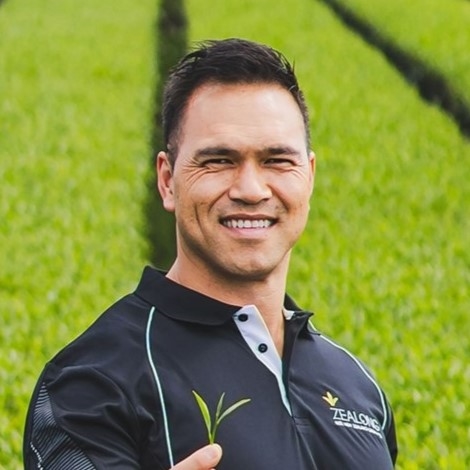 Lächelnder Mann mit schwarzem Polo-Shirt hält grüne Pflanze