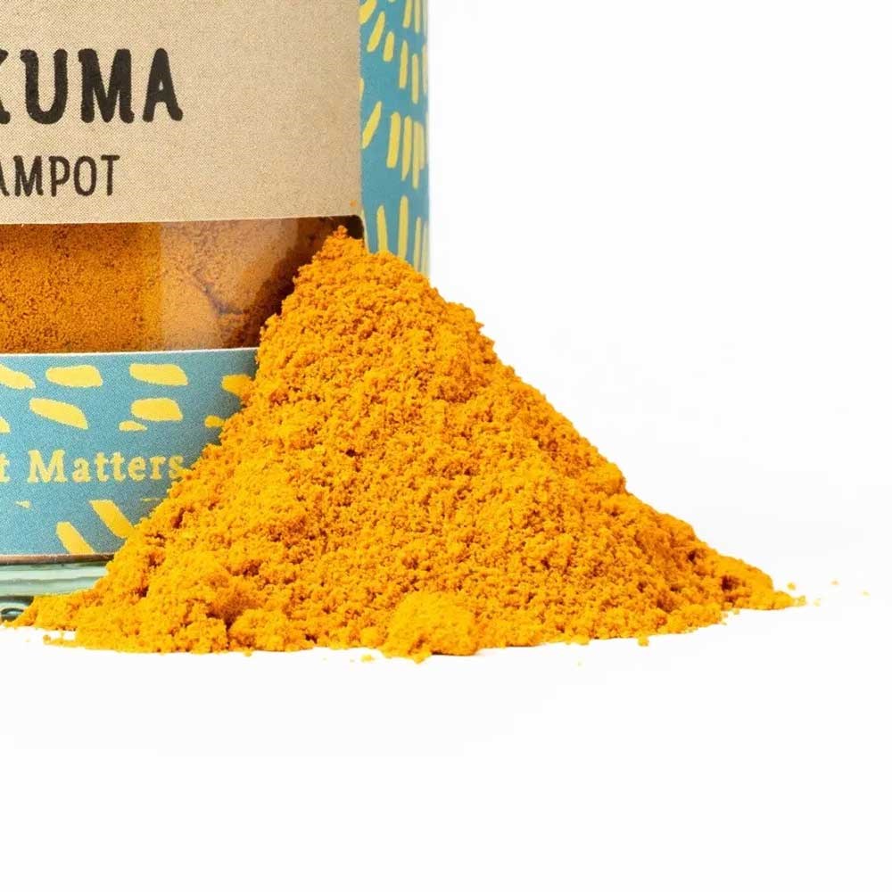 Leuchtend gelbes Kurkumapulver vor einer dekorativen Dose mit gemahlener Kurkuma